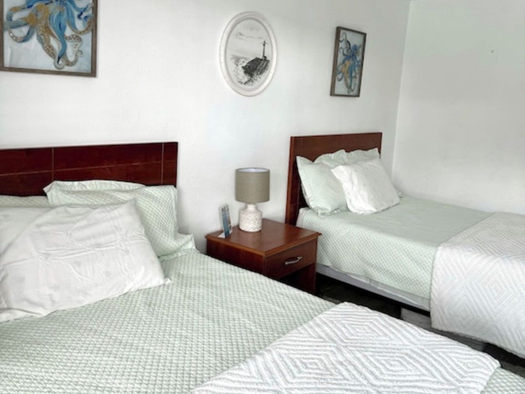 A bedroom with two beds and a nightstand