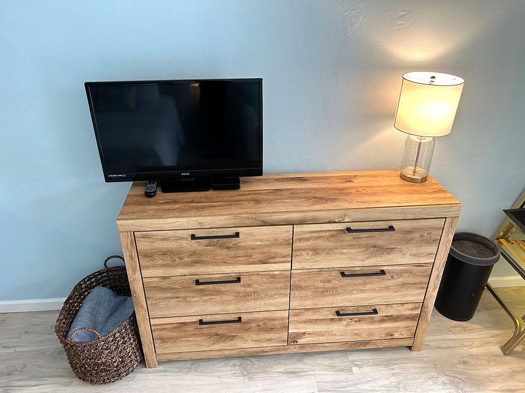 A wooden dresser with a flat screen tv on top of it