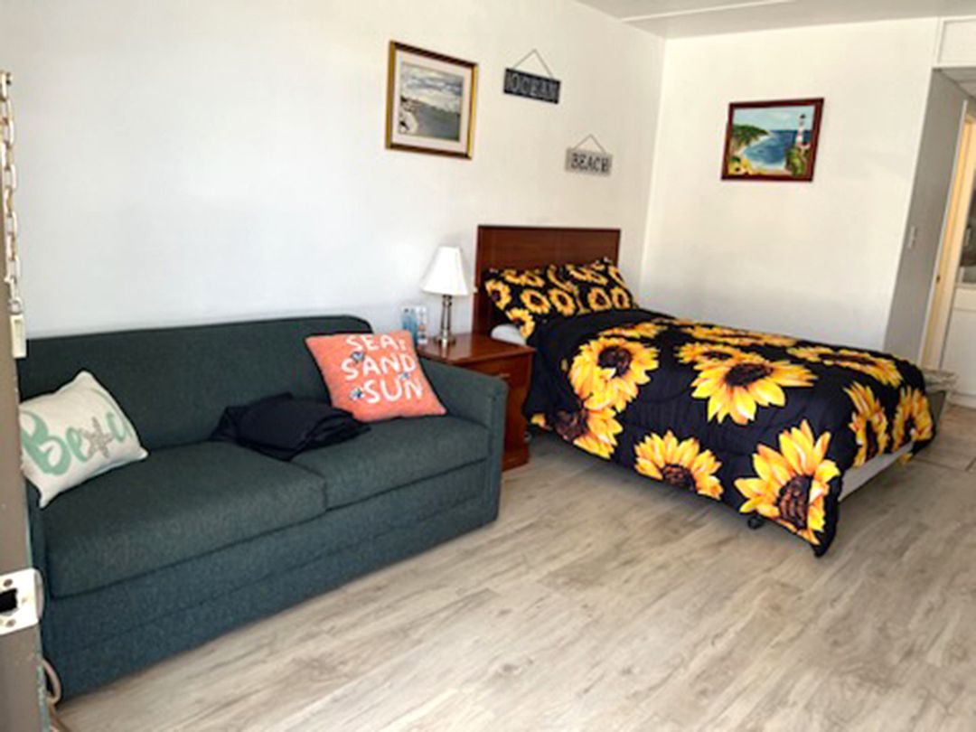 A bedroom with a couch and a bed with a sunflower blanket