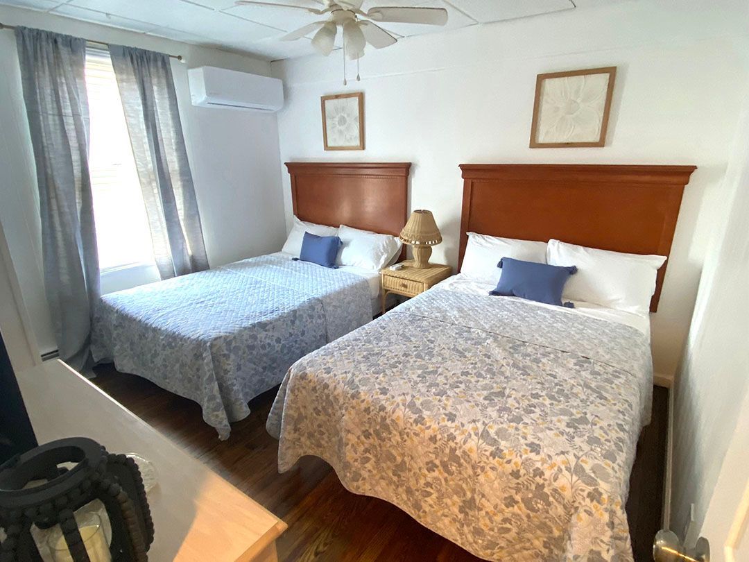 A hotel room with two beds and a ceiling fan