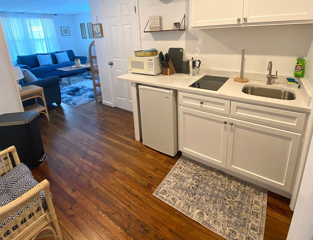 A kitchen with white cabinets, a sink, a refrigerator, and a microwave.