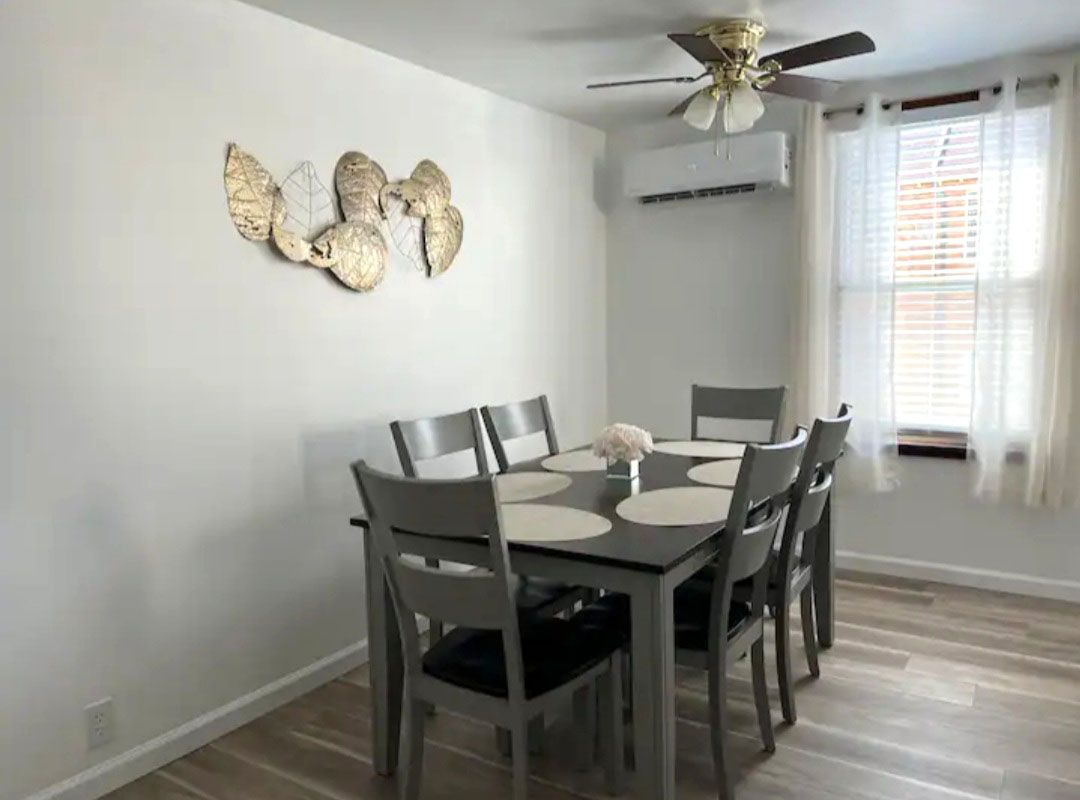 A dining room with a table and chairs and a ceiling fan.
