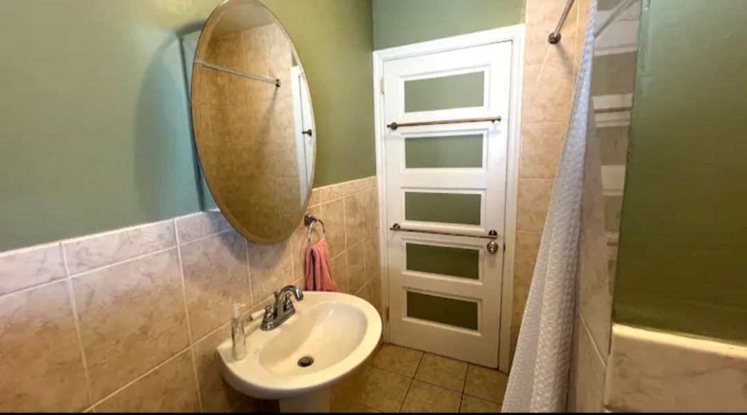 A bathroom with a sink, mirror, and shower curtain