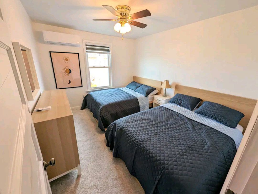 A bedroom with two beds and a ceiling fan