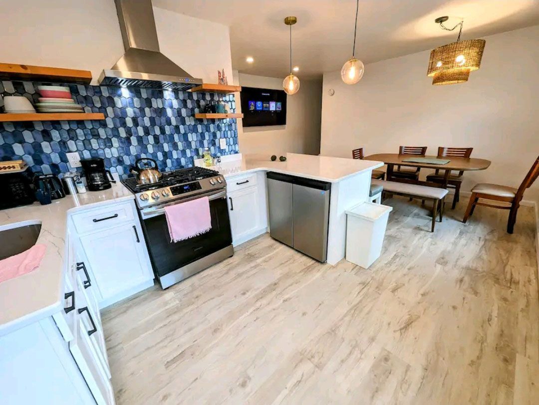 A kitchen with a stove, dishwasher, sink, chairs, and a table.