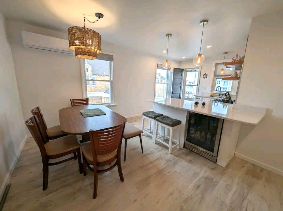 A dining room with a table and chairs and a refrigerator.