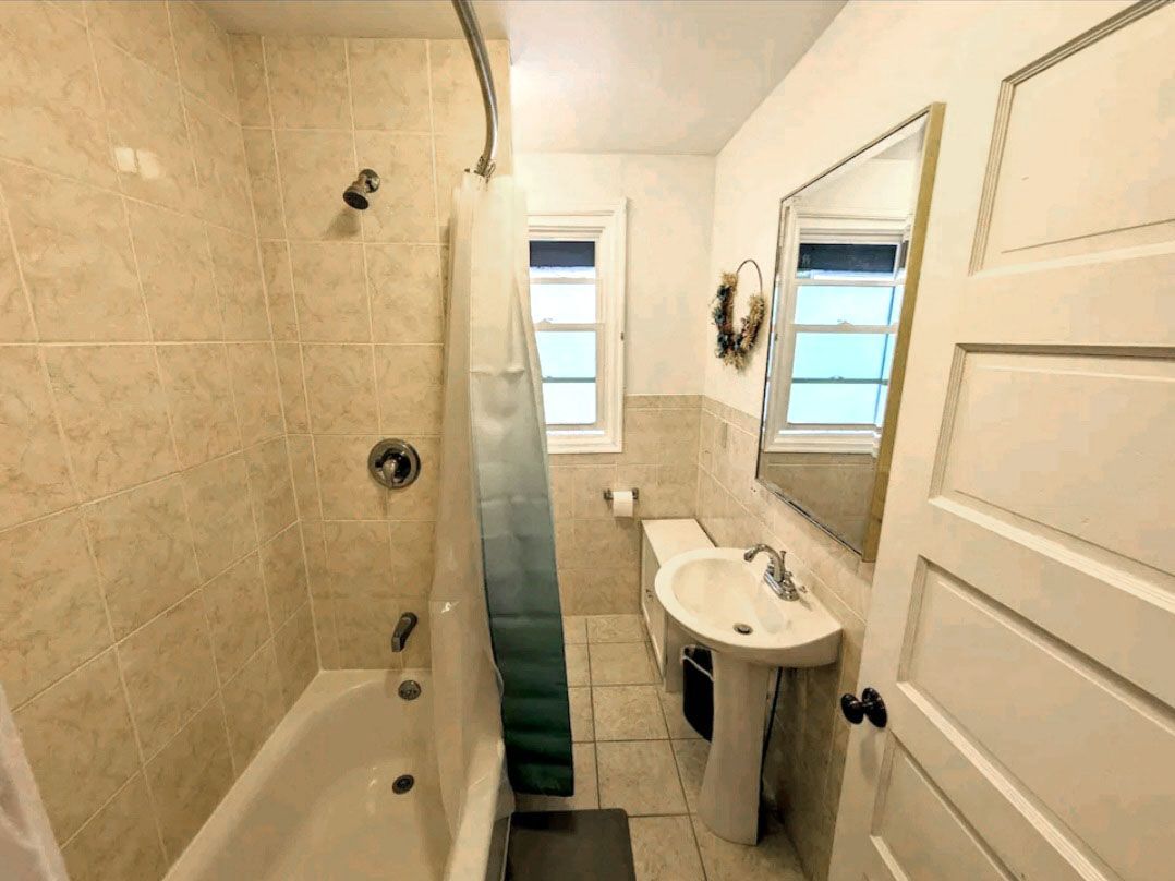 A bathroom with a tub, sink, toilet, and mirror.