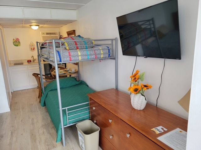 A bedroom with bunk beds, a dresser, and a flat screen TV