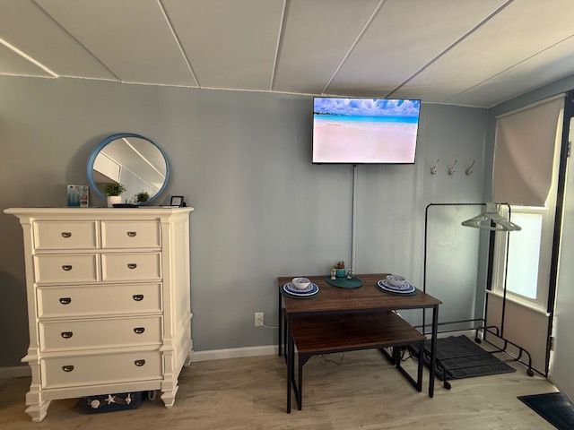 A living room with a dresser a table and a flat screen tv