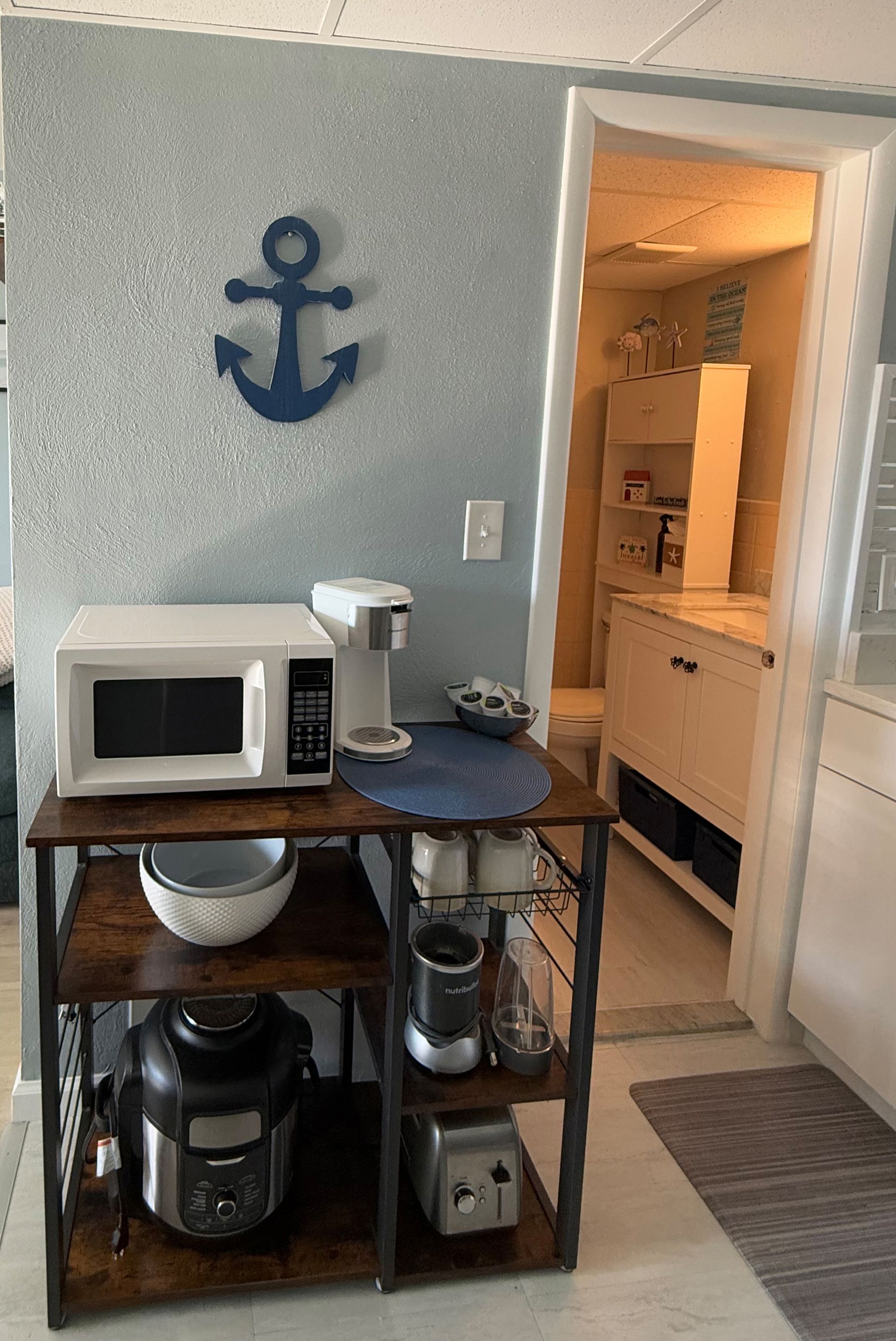A kitchen with a microwave , coffee maker , pots and pans , and an anchor on the wall.