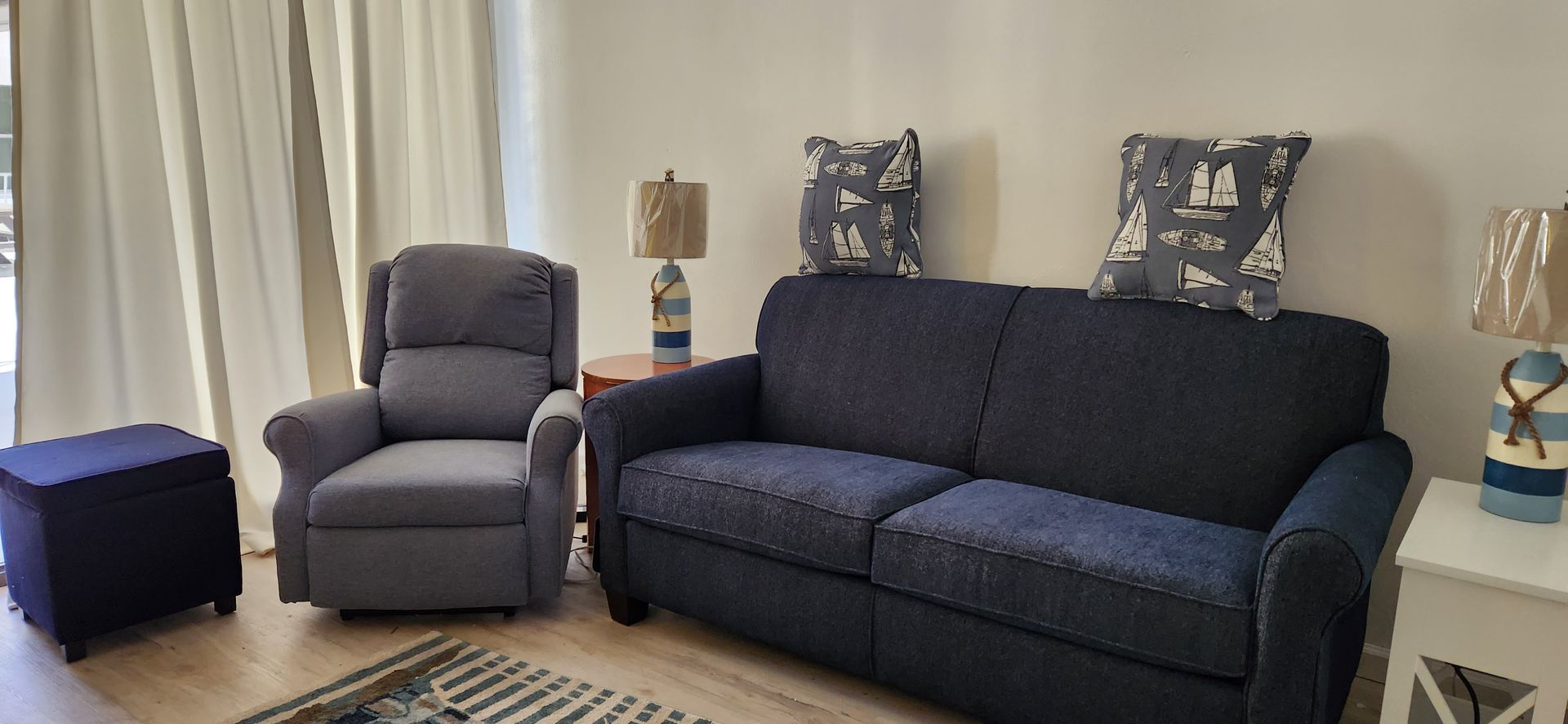 Living room with blue sofa, recliner, ottoman, and nautical-themed decor.