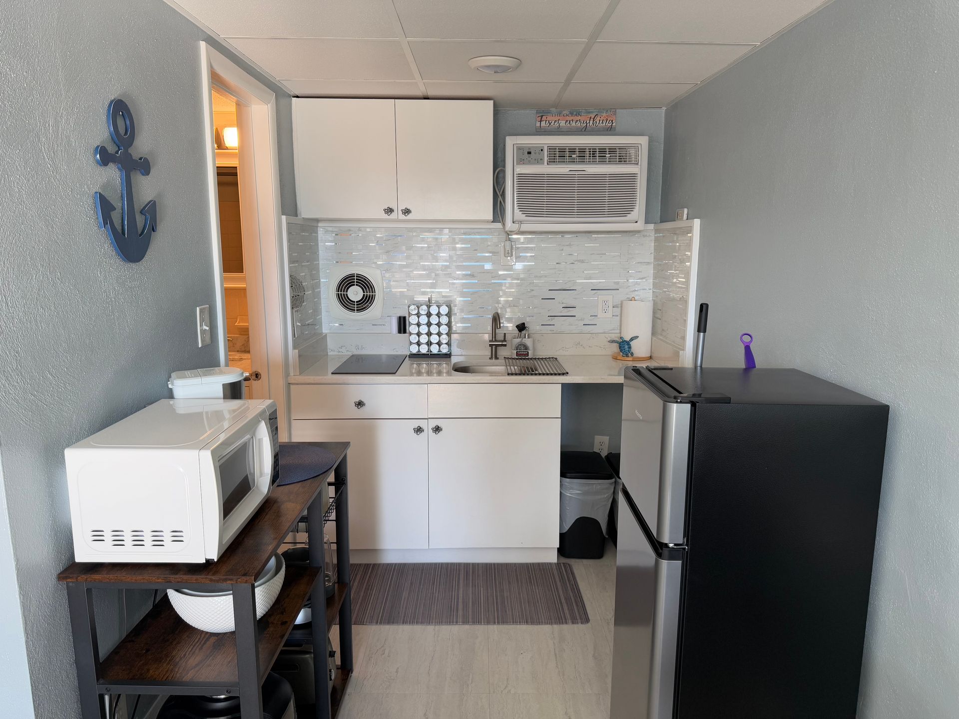 A small kitchen with a microwave, refrigerator and sink