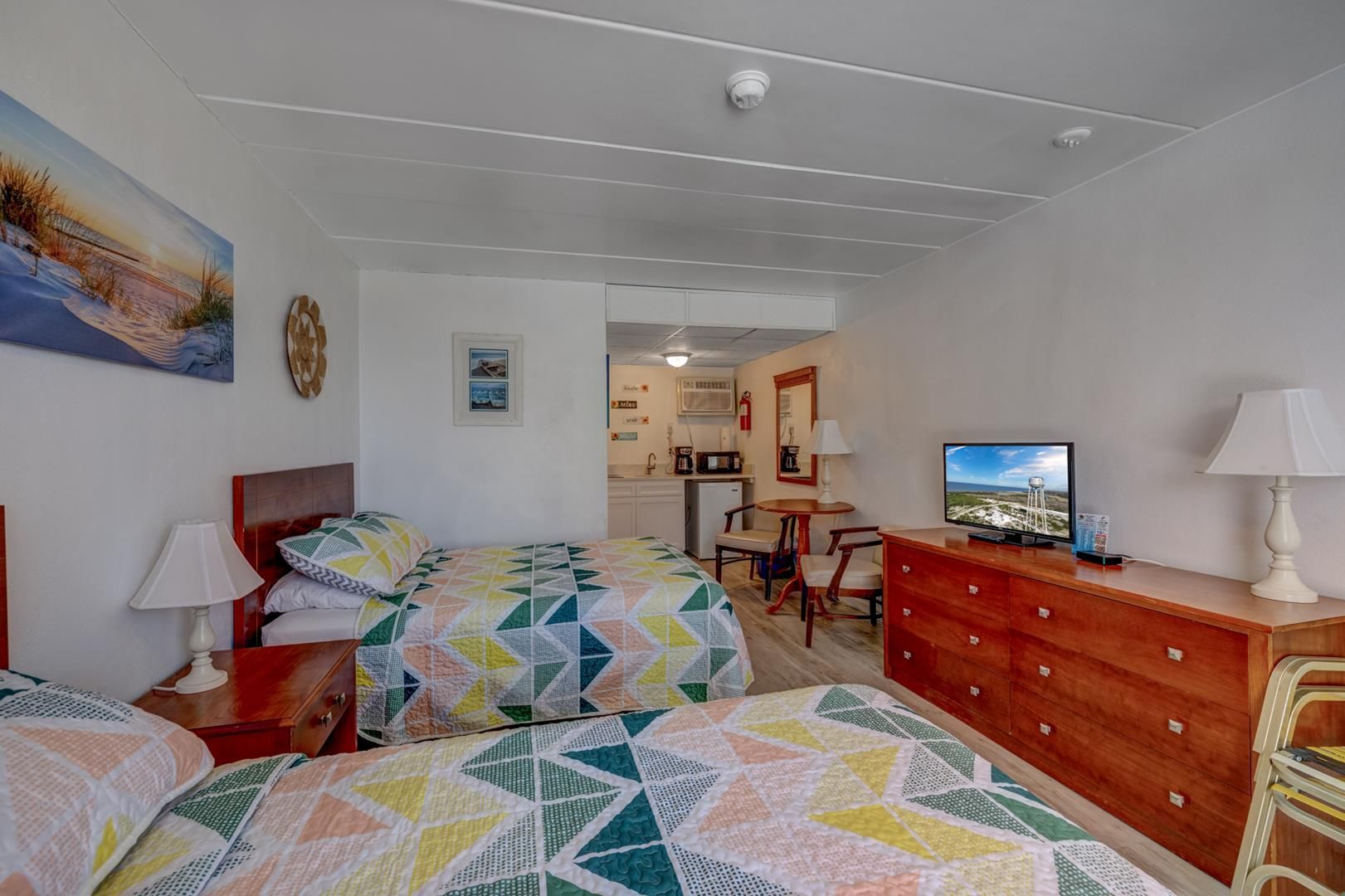 A hotel room with two beds, a dresser, and a television.