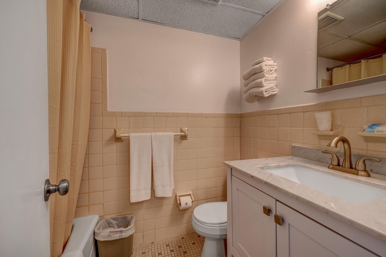 A bathroom with a toilet, sink, and mirror.