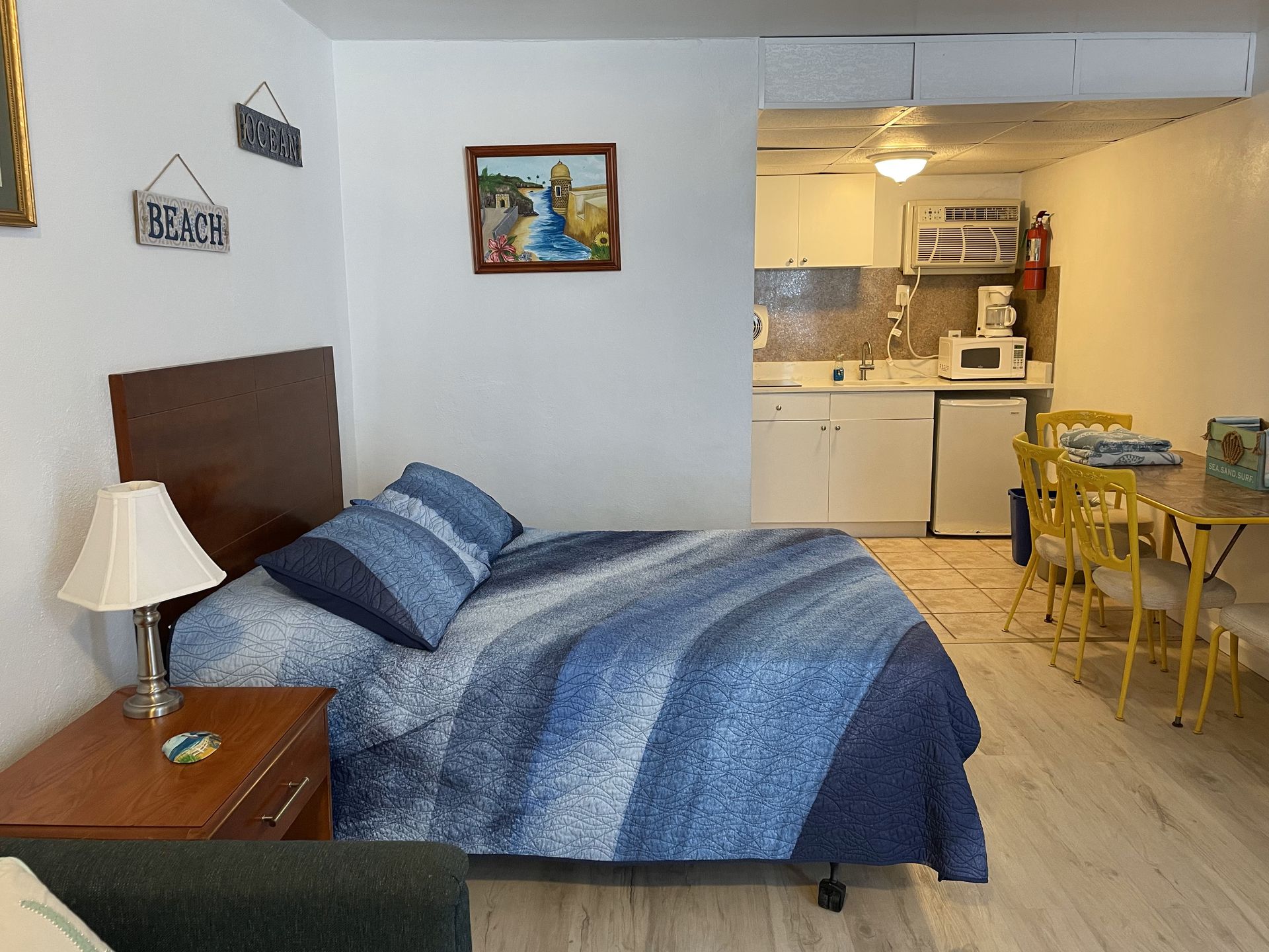 A bedroom with a bed and a kitchen with a sign that says beach