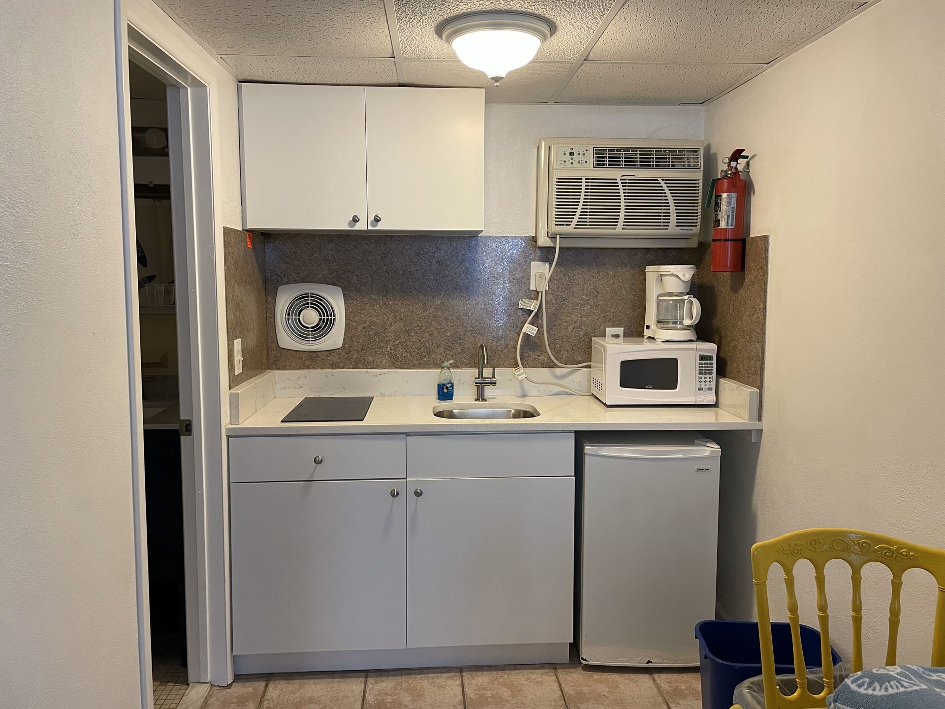 A small kitchen with white cabinets and a microwave