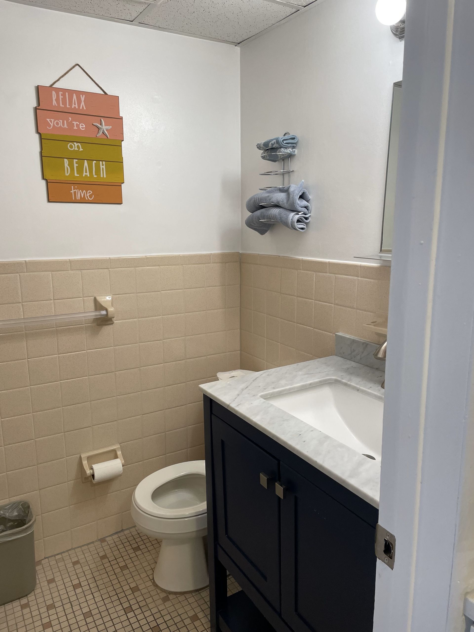 A bathroom with a toilet a sink and a sign that says beach