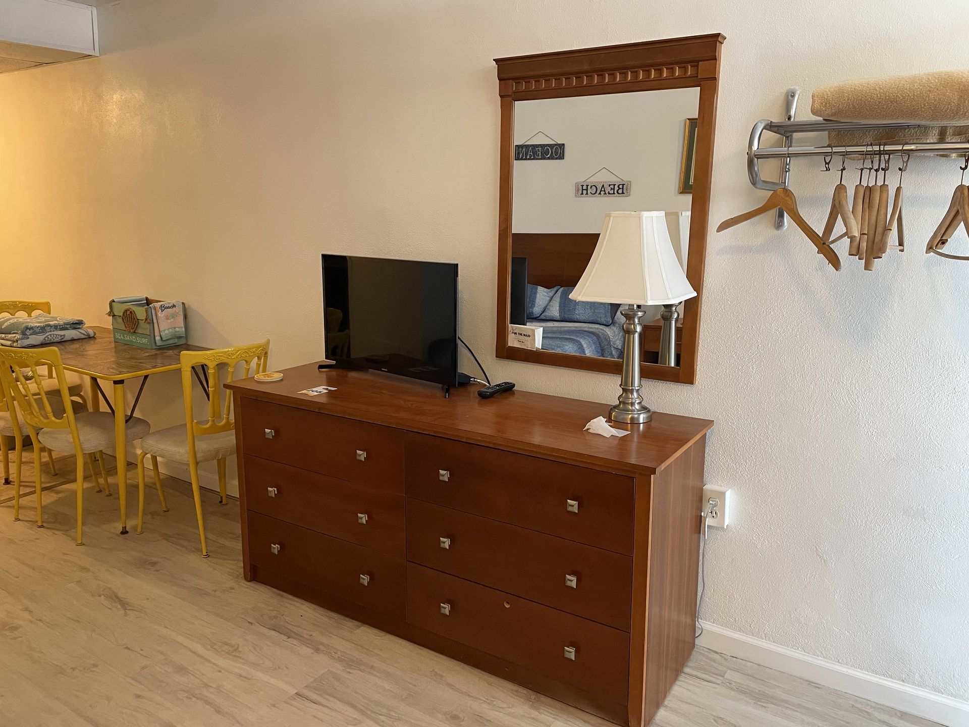 A living room with a dresser, television, lamp, and mirror