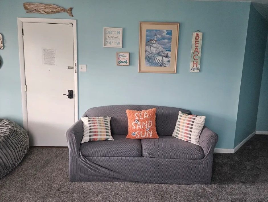 A living room with a couch and a pillow that says sea sand sun