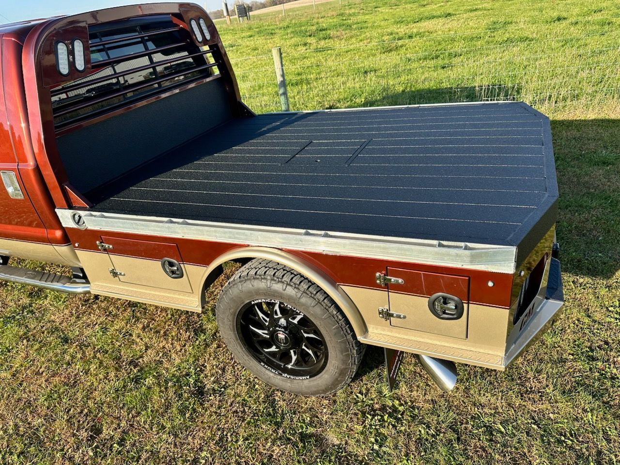 A truck with a flat bed is parked in a grassy field.
