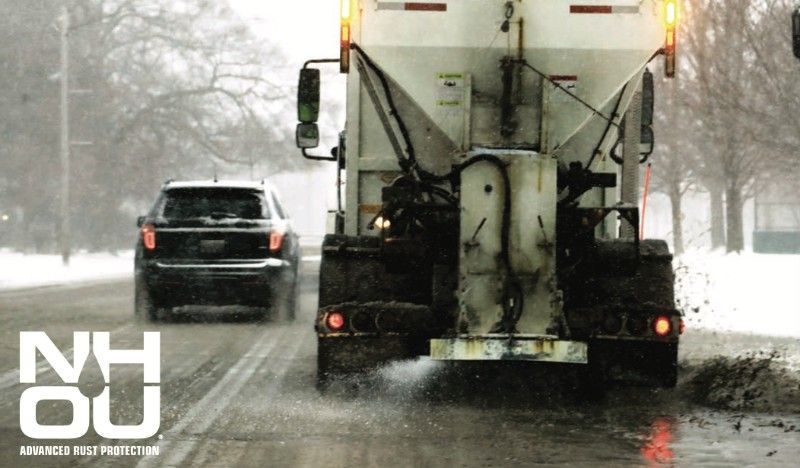 A truck is driving down a snowy road with nh ou written on the bottom