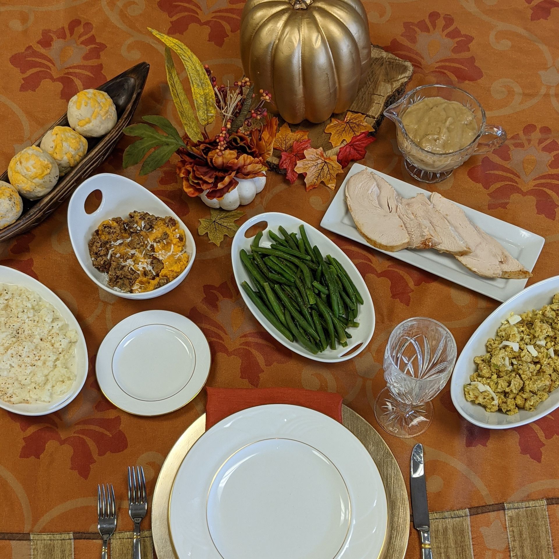 Thanksgiving table with turkey, gravy, sides, and a pumpkin centerpiece.