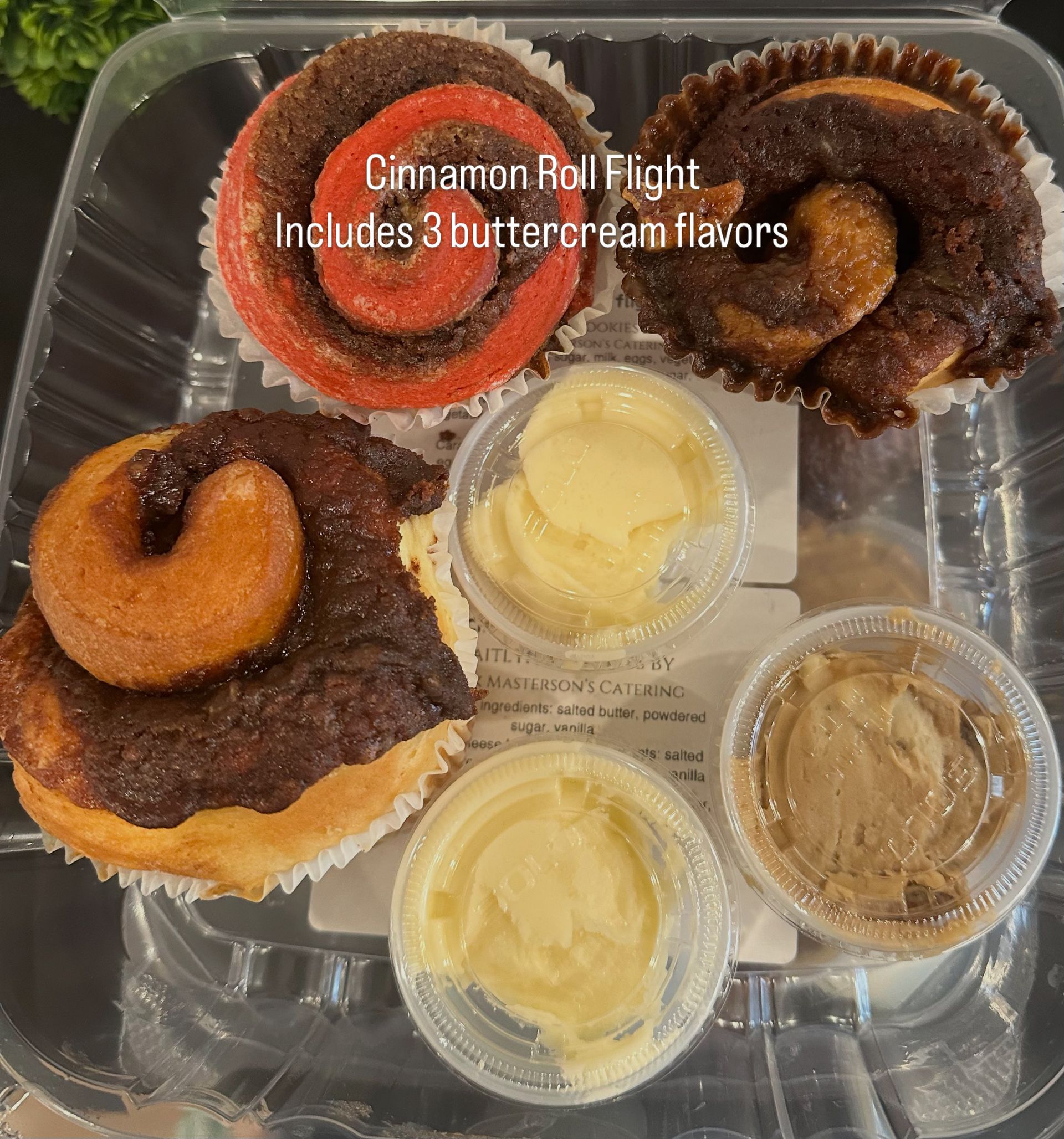 Assorted cinnamon roll flight with three frostings in clear takeout tray