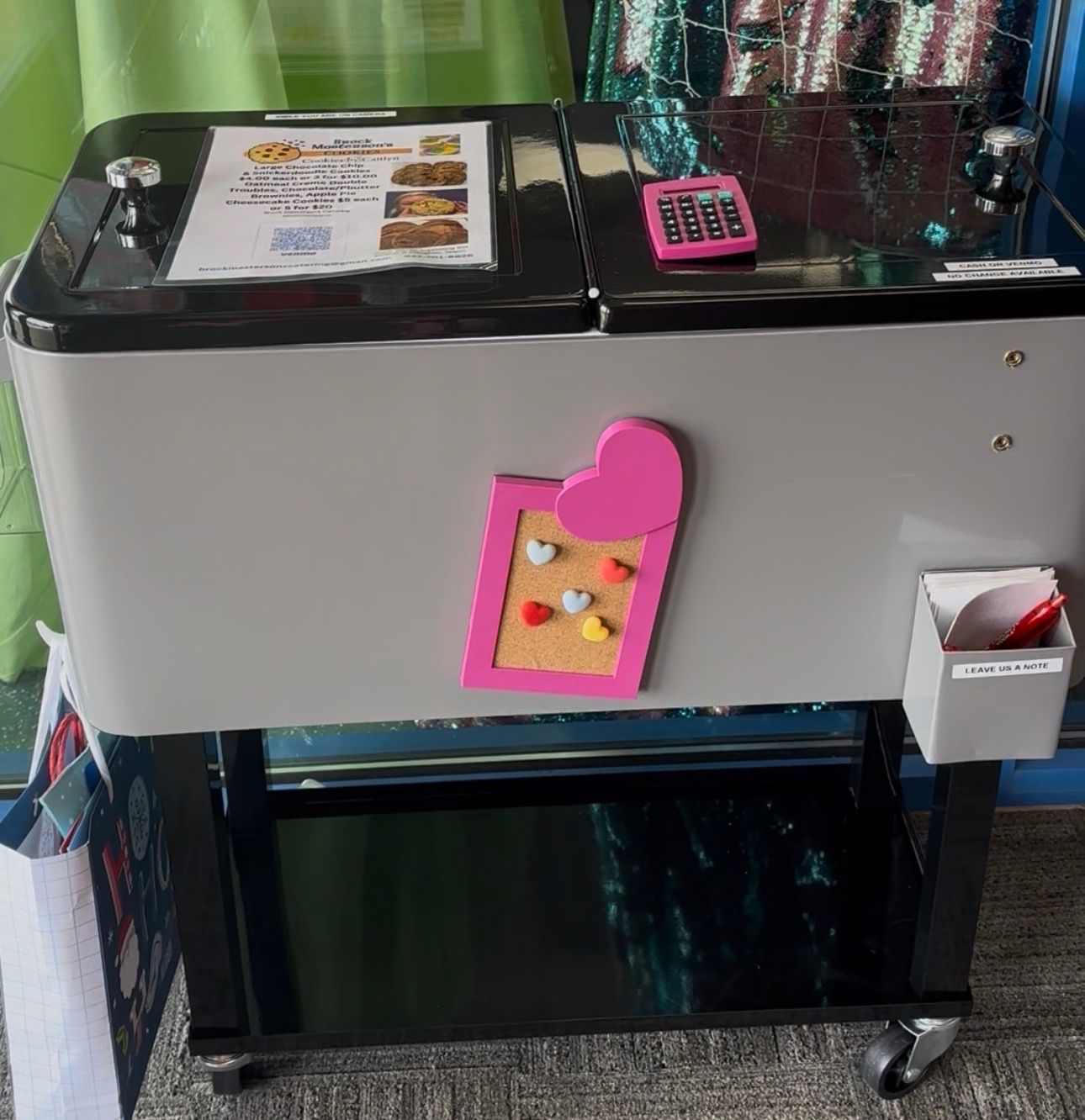 Stainless steel machine with a black top, pink keypad, and a small hanging decoration in front.