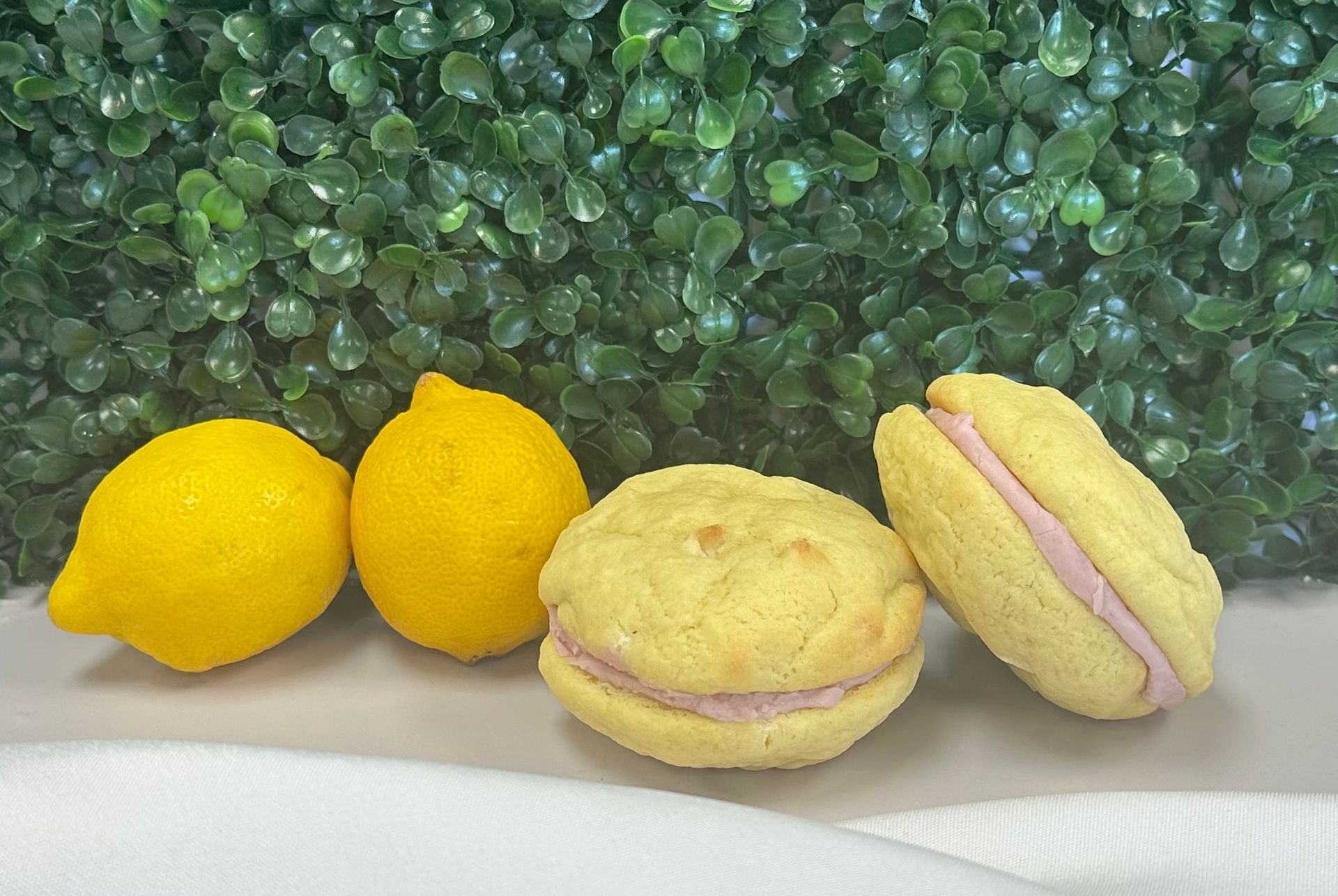 Three lemon-shaped pastries on a white plate against a green leafy background