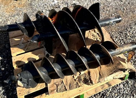 A bunch of drill bits are sitting on top of a wooden pallet.