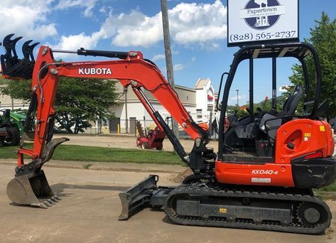 A red kubota excavator is parked on the side of the road.