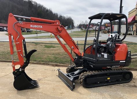 A small red excavator is parked on the side of the road.