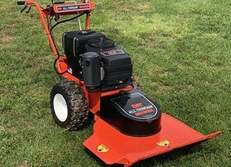 A red and black lawn mower is sitting on top of a lush green lawn.