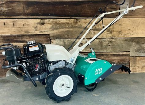 A small tractor is parked in front of a wooden wall.