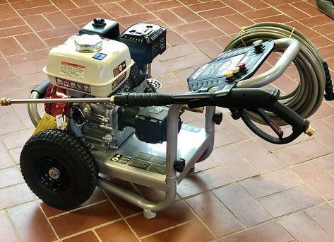 A high pressure washer with a hose attached to it is sitting on a tiled floor.