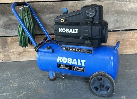 A kobalt air compressor is sitting on a wooden table.