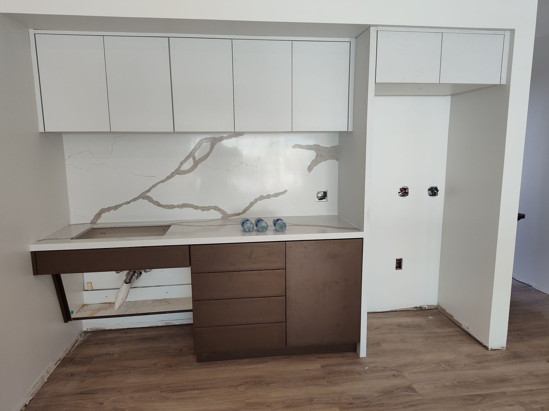 A kitchen with white cabinets and a marble counter top.