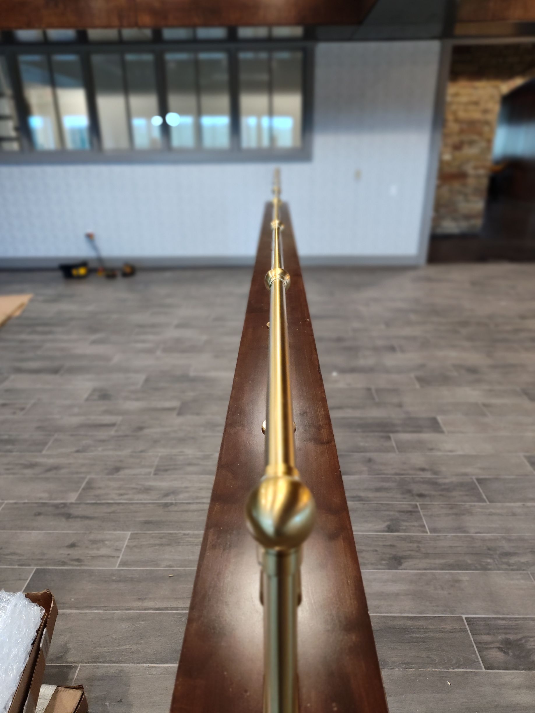 A close up of a brass railing on a wooden staircase.