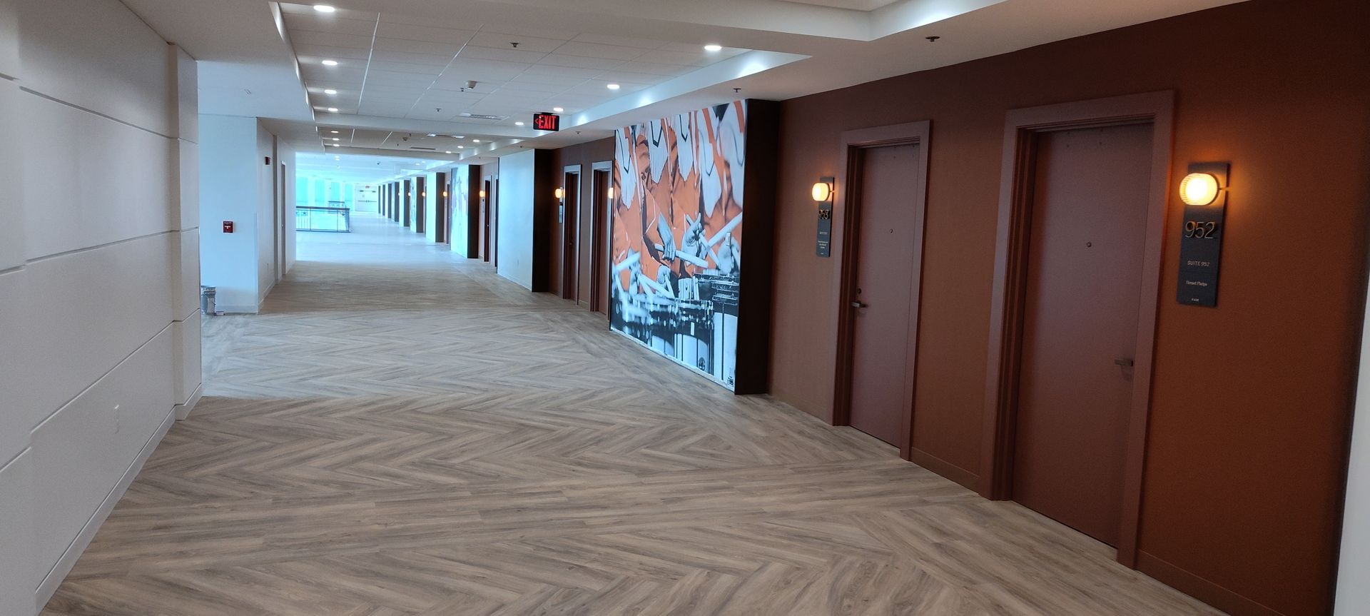 A long hallway with a lot of doors and a picture on the wall.