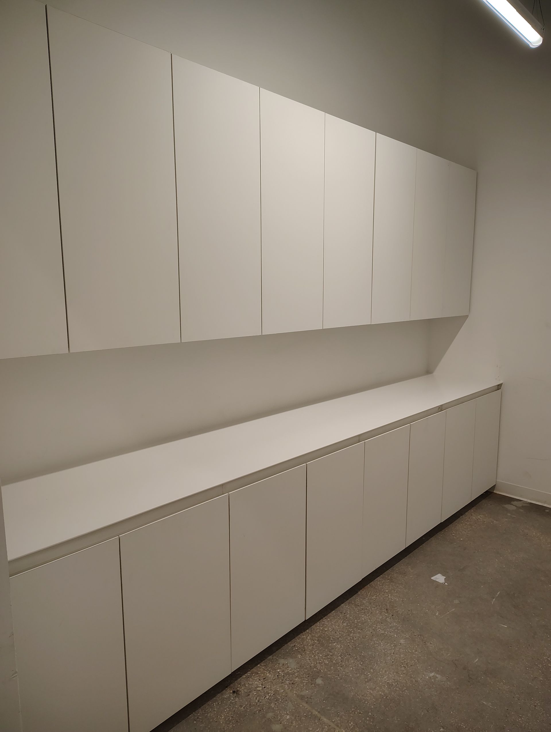 A room with a lot of white cabinets on the wall.