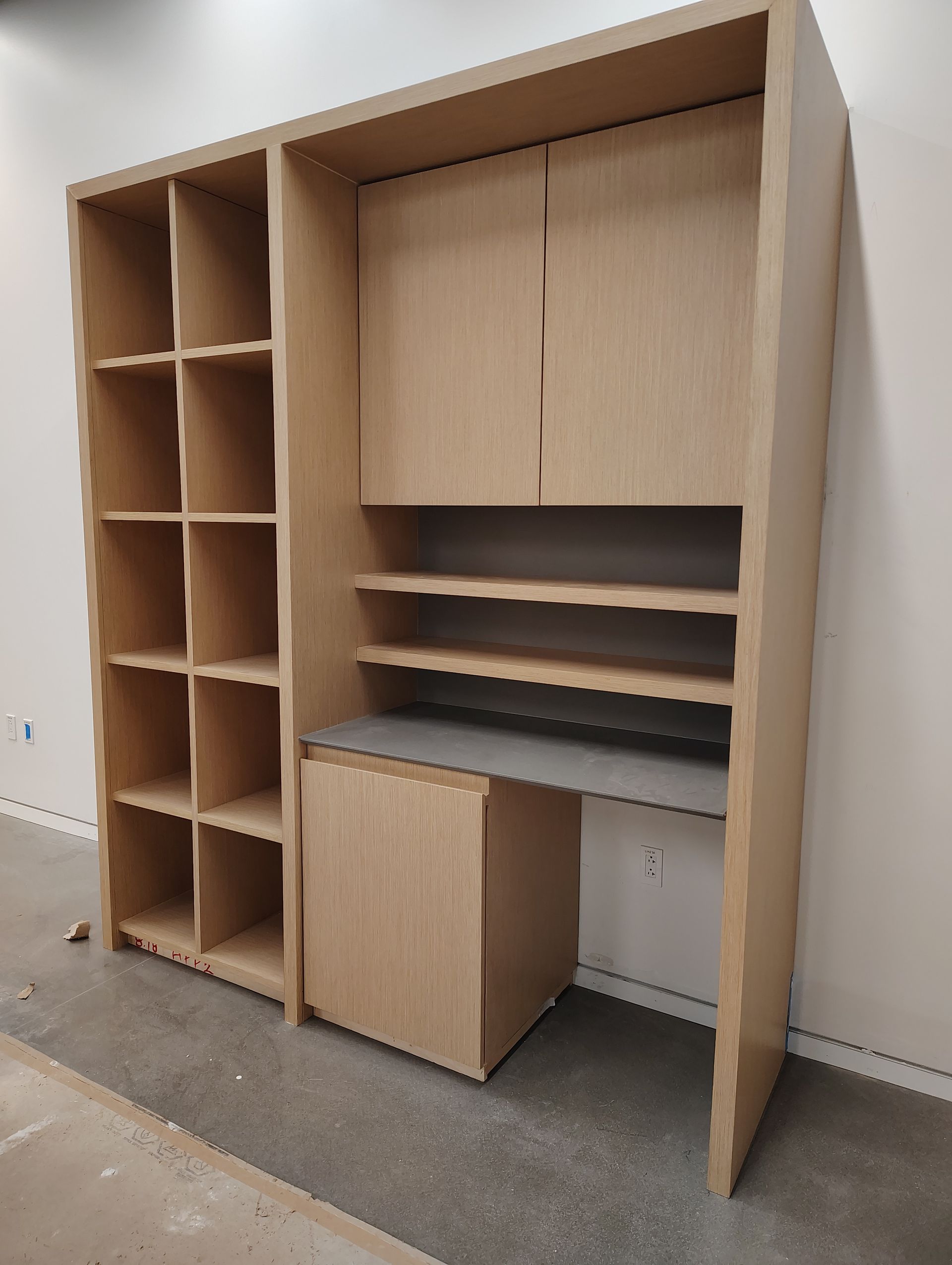 A wooden cabinet with shelves and a desk in a room.