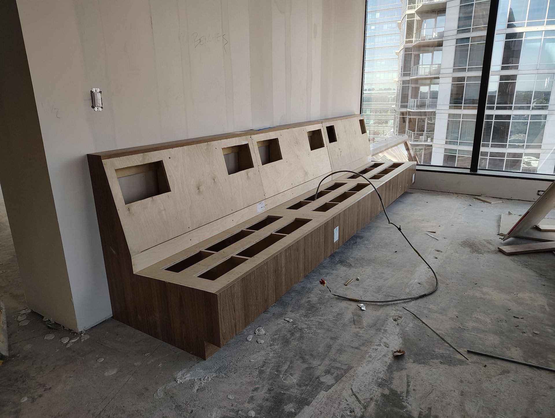 A wooden bench is sitting in a room with a large window.