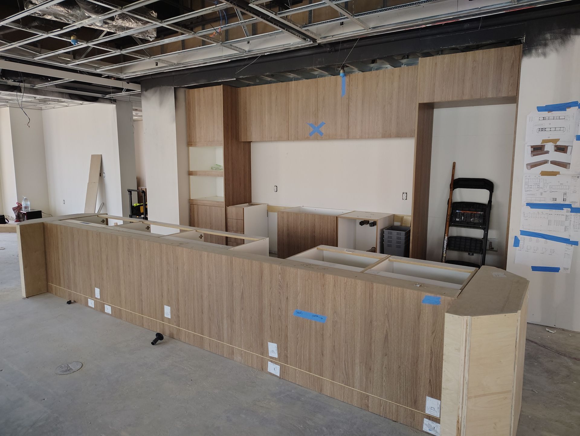 A kitchen is being built in a building with wooden cabinets.