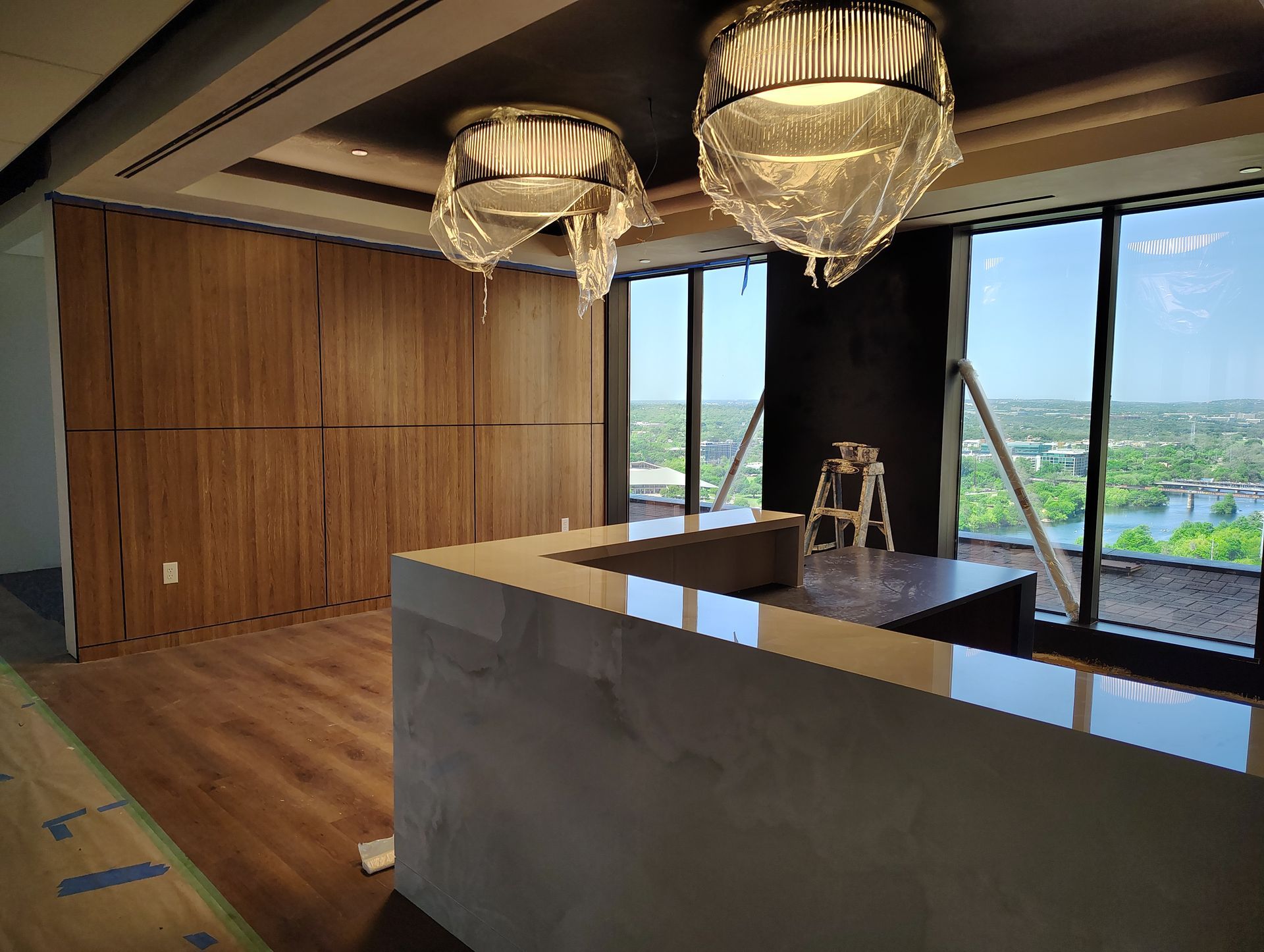 A large empty room with a ladder in the corner and two chandeliers hanging from the ceiling.