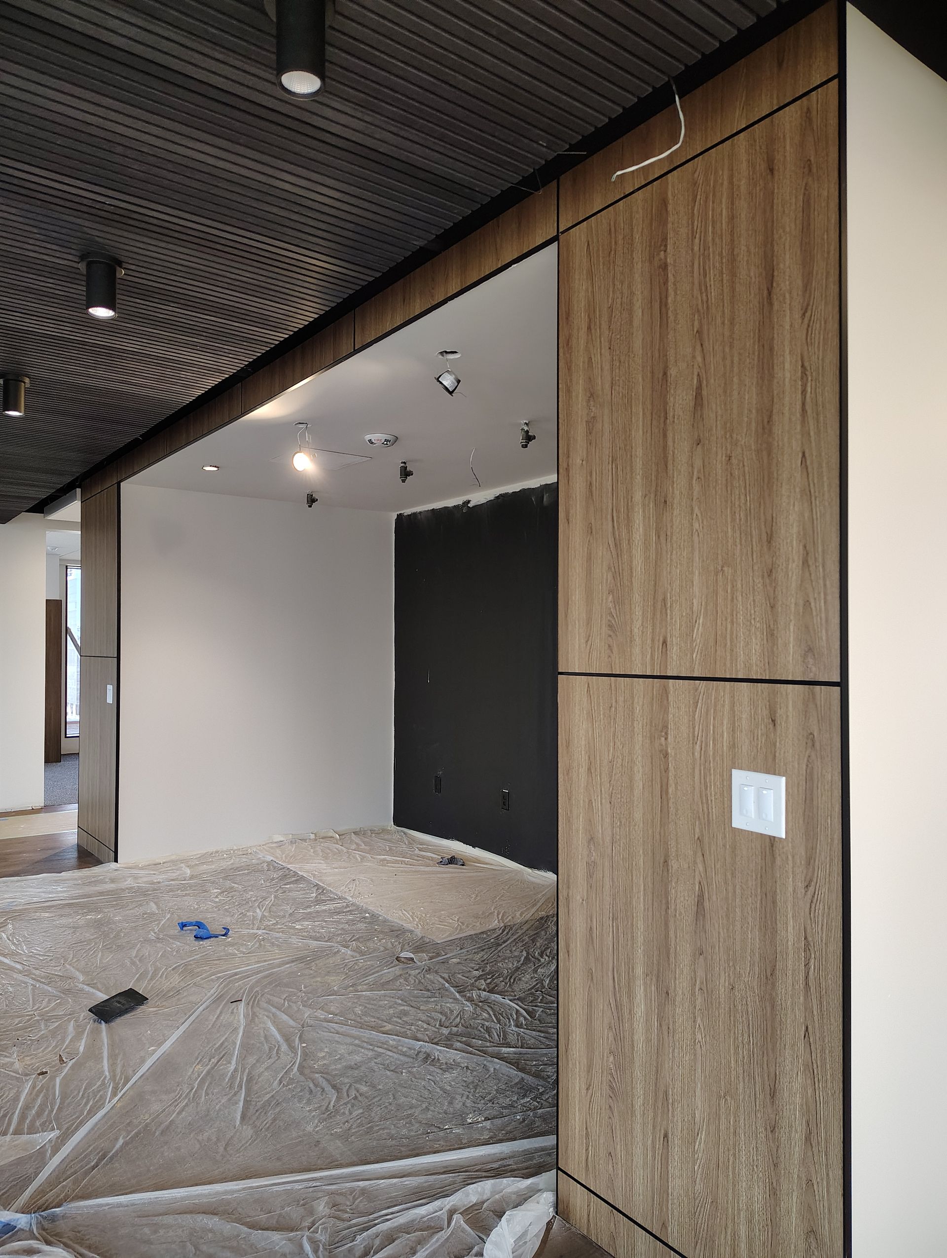 A room with a wooden wall and a black wall.