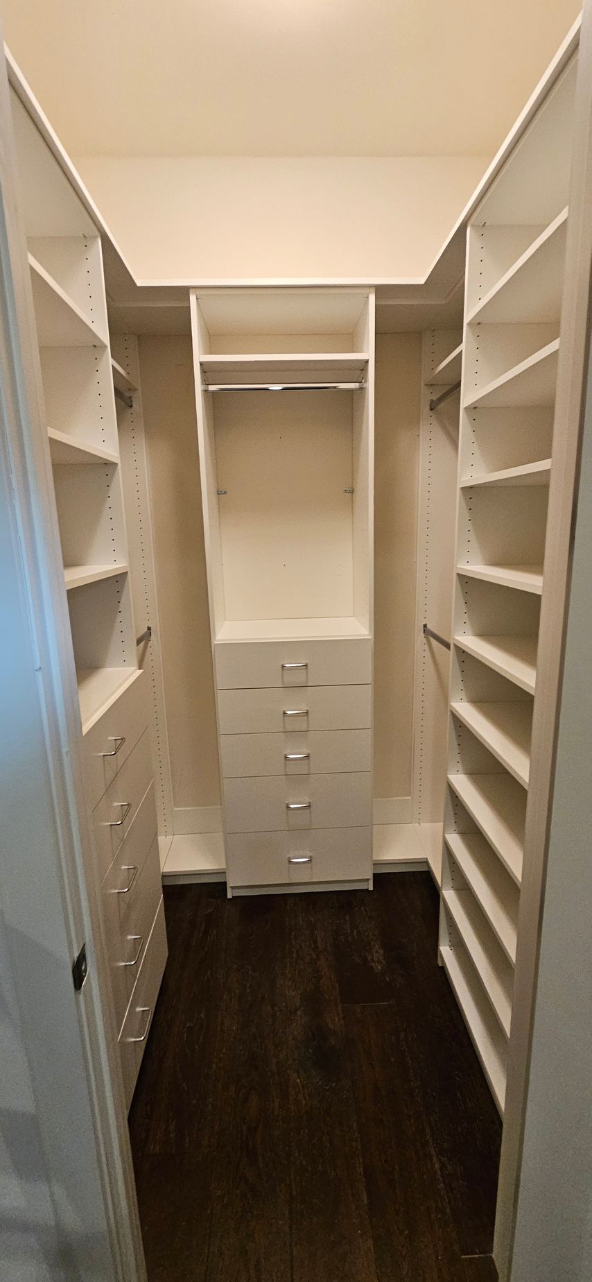 A walk in closet with lots of shelves and drawers.