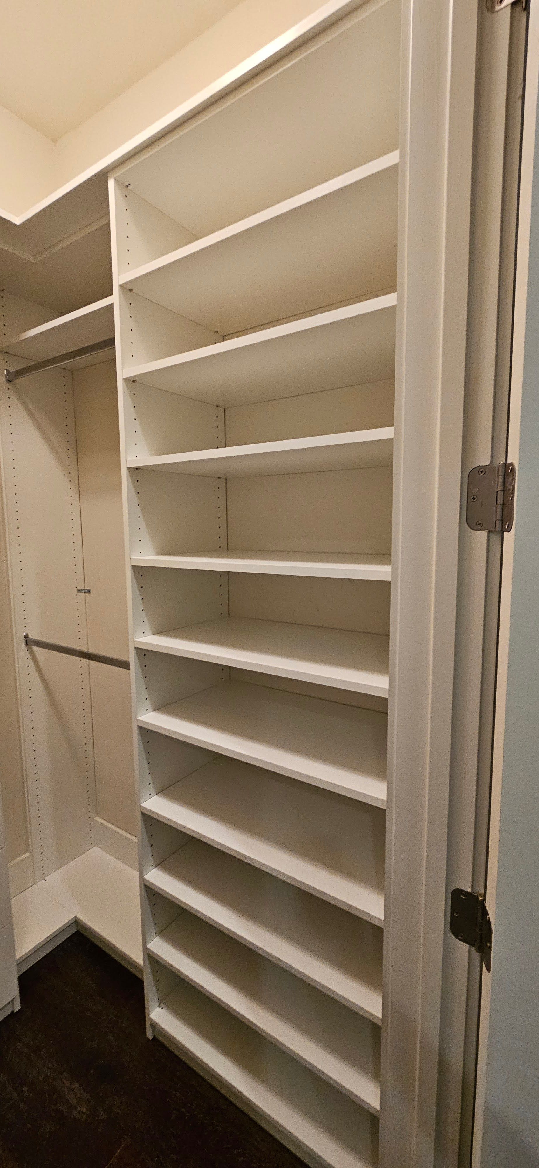 A walk in closet with lots of shelves and a door.