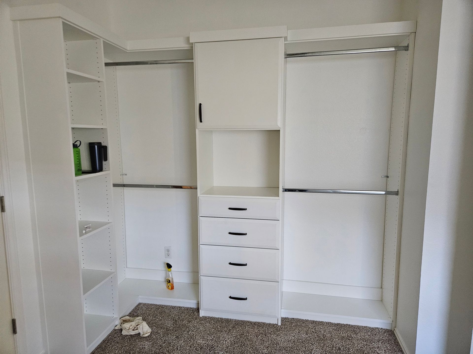 A walk in closet with white shelves and drawers in a bedroom.