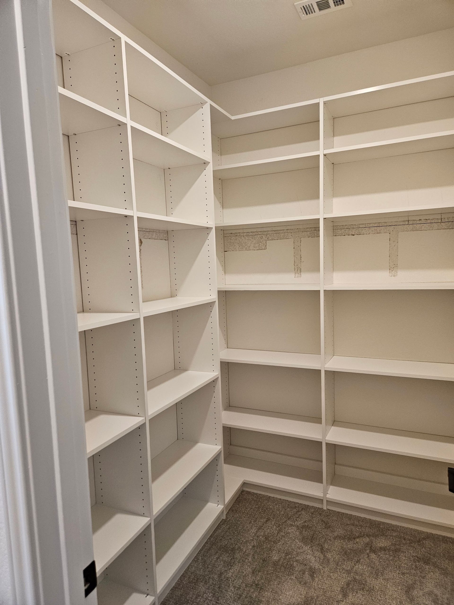 A walk in closet with lots of shelves and a door.