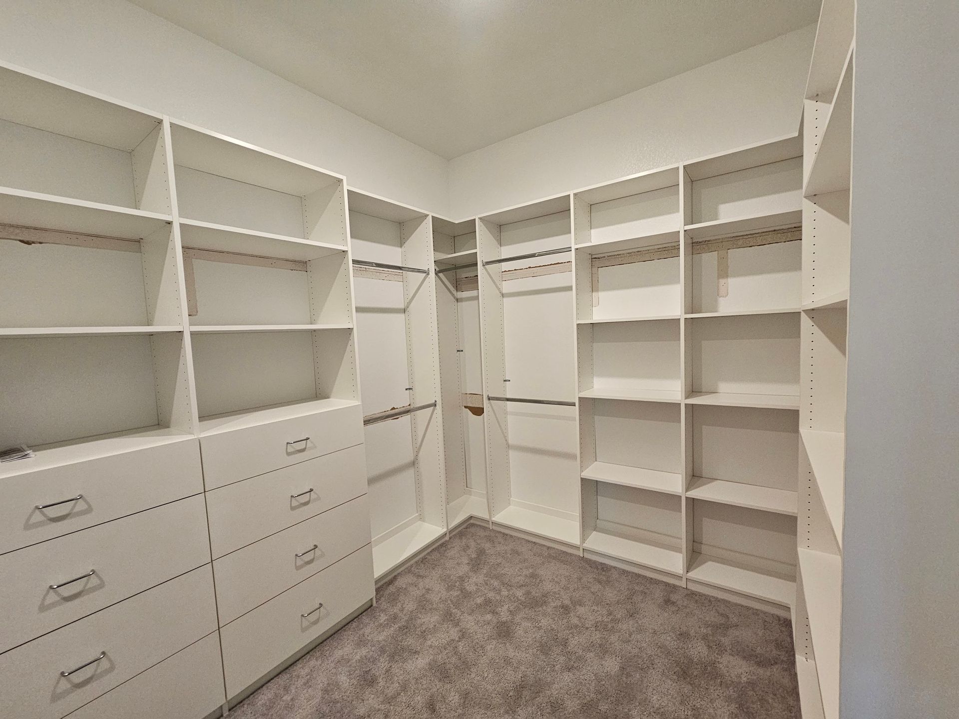 A walk in closet with lots of shelves and drawers.